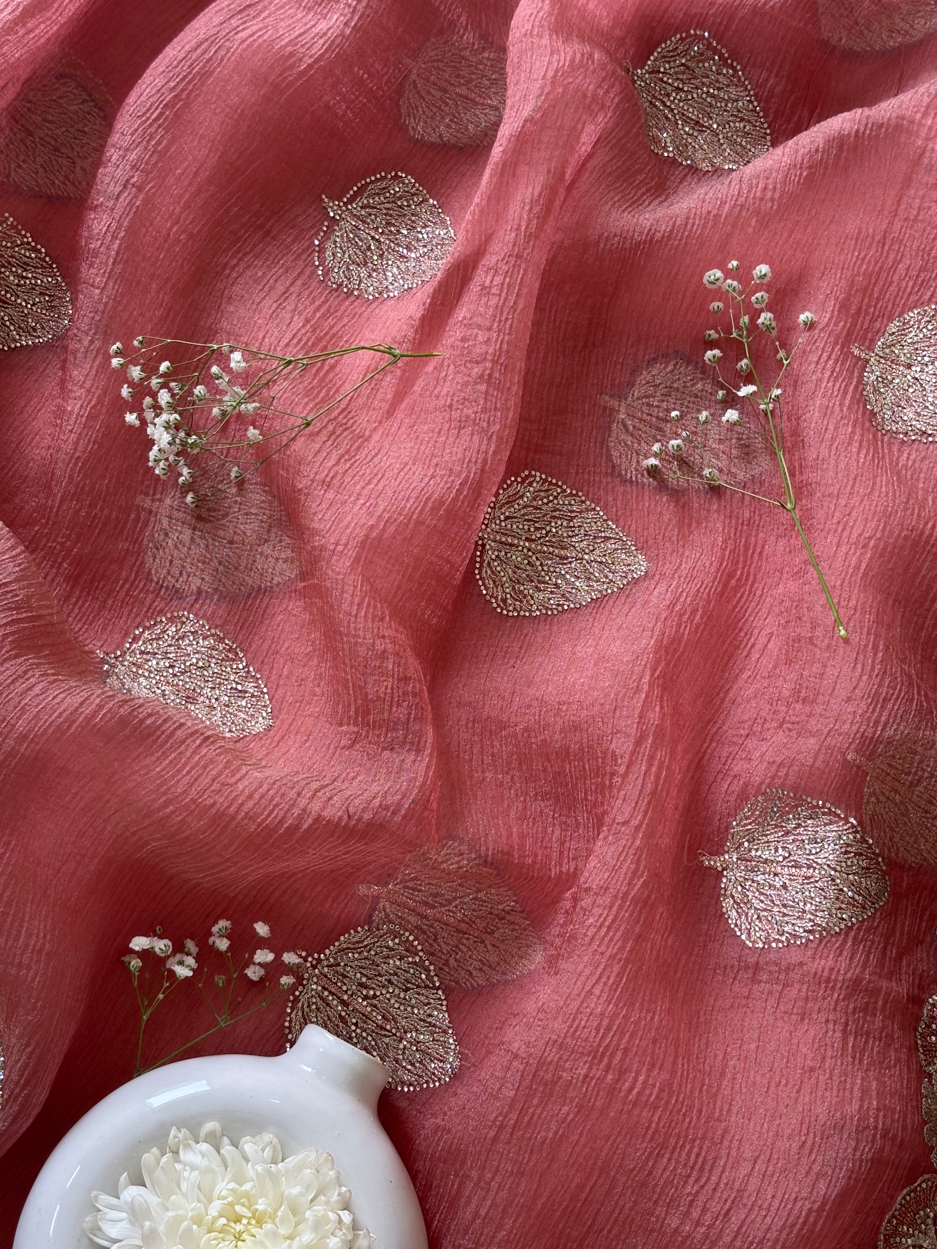 Pink fabric with gold leaf patterns and small white flowers on a pink background