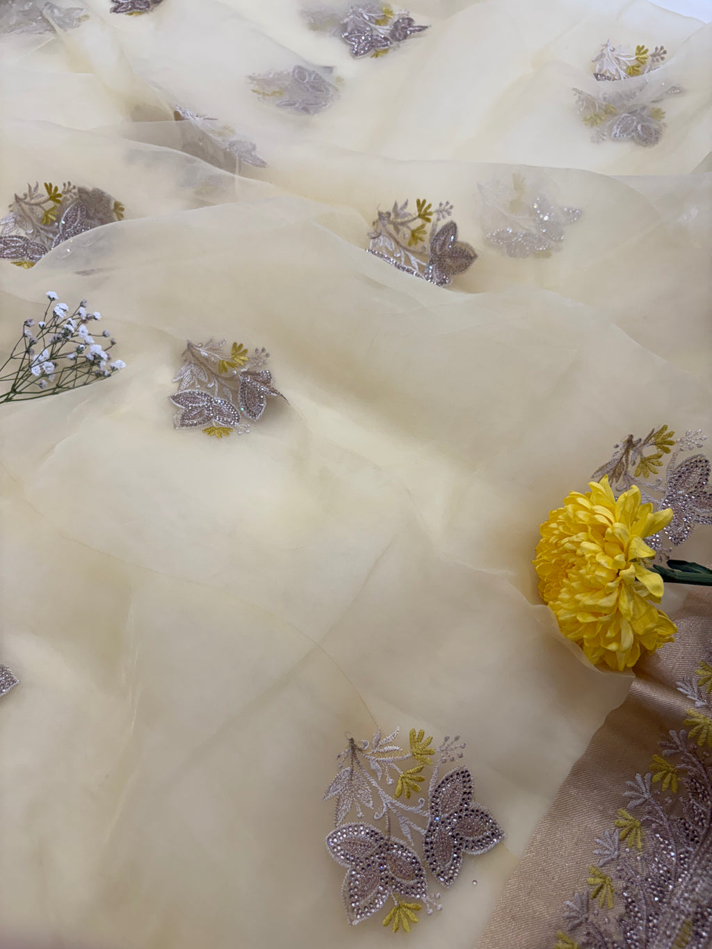 Delicate fabric with floral embroidery and a yellow flower on a light background
