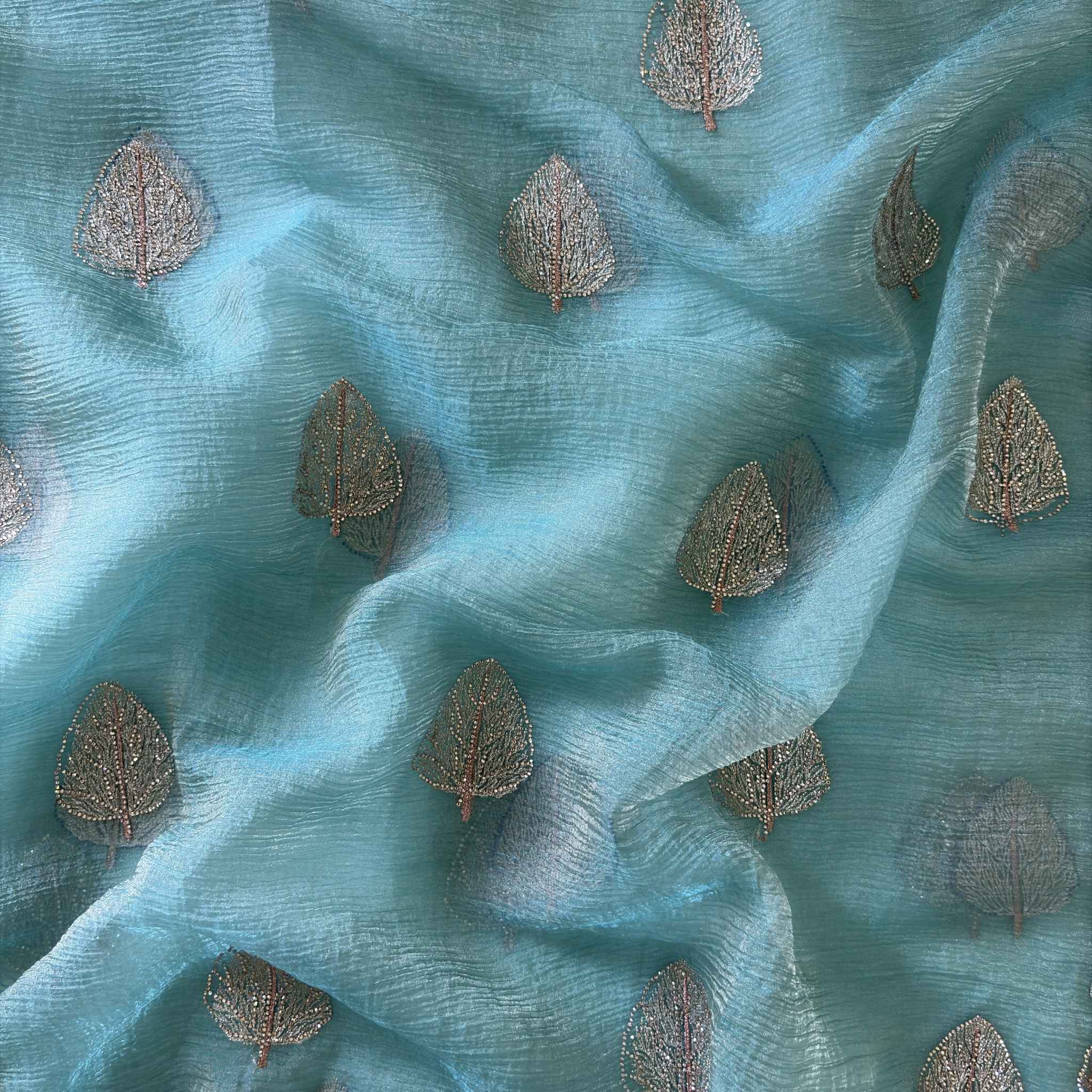 Teal fabric with embroidered leaf patterns
